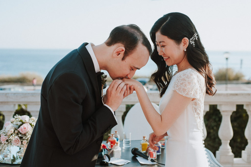 destination wedding cascais - groom kissing bride's hand