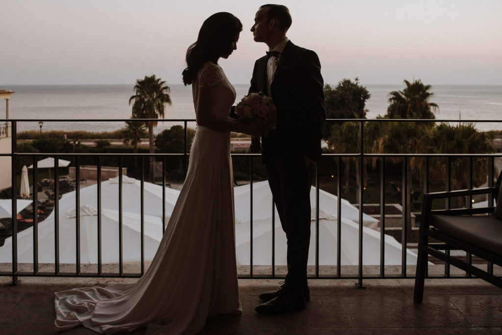 destination wedding cascais - bride and groom at hotel balcony bysunset