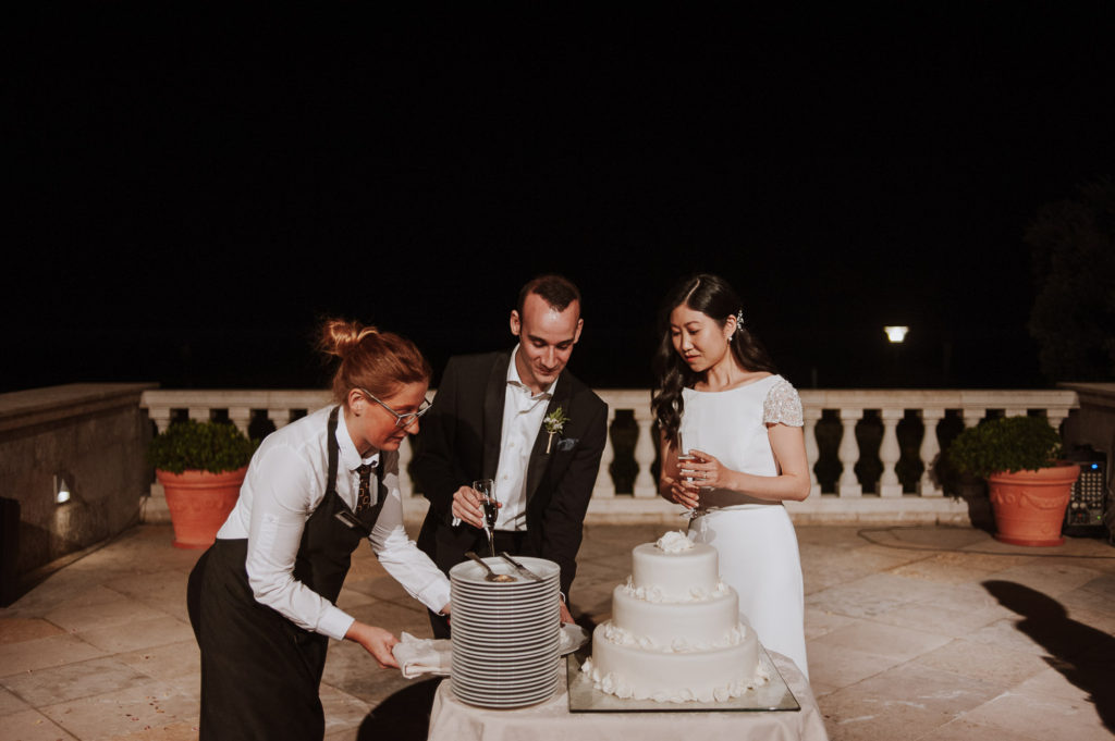 destination wedding cascais - couple cutting cake with hotel staff help